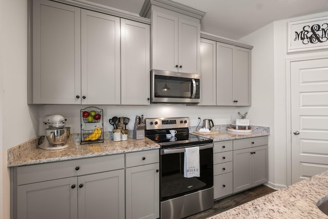 kitchen featuring dark wood-type flooring, light stone countertops, gray cabinetry, and stainless steel appliances