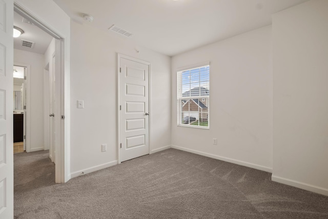 unfurnished bedroom featuring baseboards, carpet, and visible vents