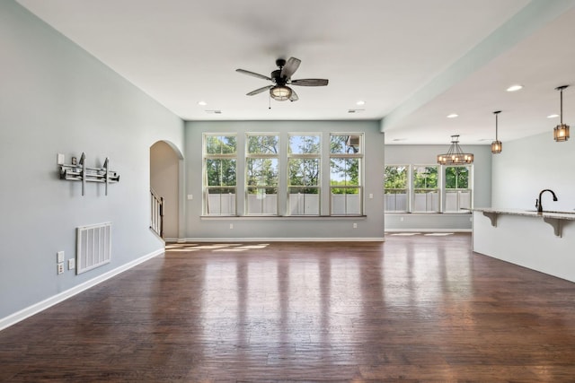 unfurnished living room with recessed lighting, visible vents, plenty of natural light, and ceiling fan with notable chandelier