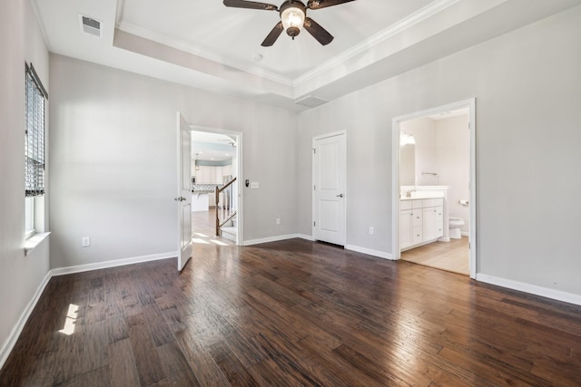 unfurnished bedroom featuring crown molding, visible vents, wood finished floors, baseboards, and a raised ceiling