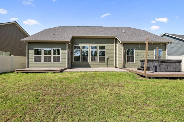 rear view of house with fence, a deck, a patio area, a hot tub, and a yard