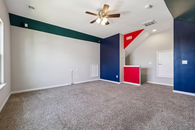 carpeted spare room featuring visible vents, a ceiling fan, baseboards, and vaulted ceiling