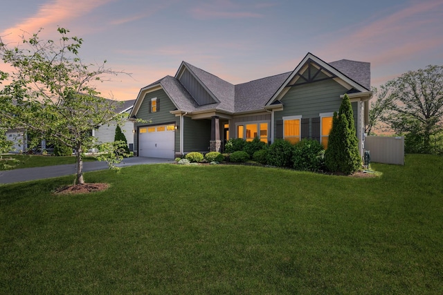 craftsman-style home featuring a lawn, an attached garage, a shingled roof, and aphalt driveway