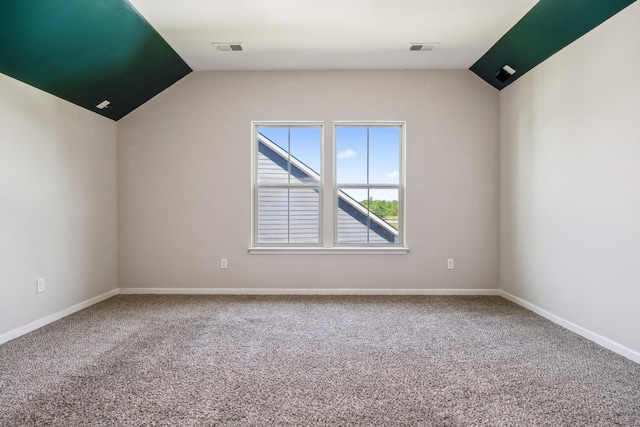 carpeted spare room with visible vents, baseboards, and lofted ceiling