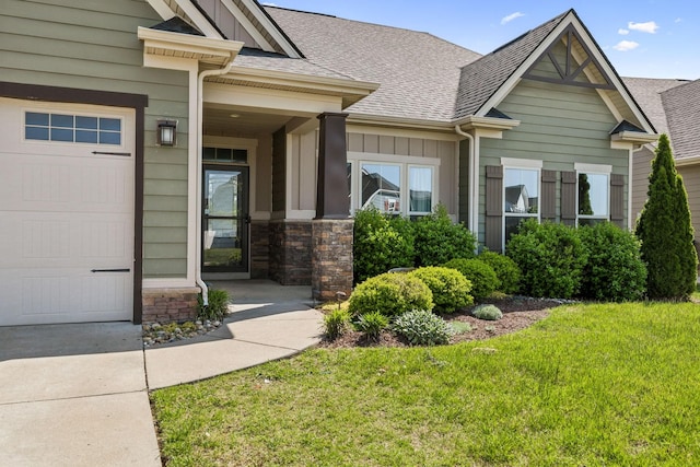 view of exterior entry with a garage, board and batten siding, roof with shingles, and a yard
