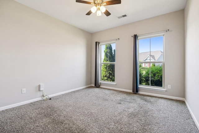 carpeted empty room featuring baseboards, a ceiling fan, and visible vents