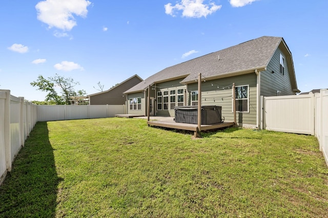 back of house with a lawn, a fenced backyard, a hot tub, and a deck
