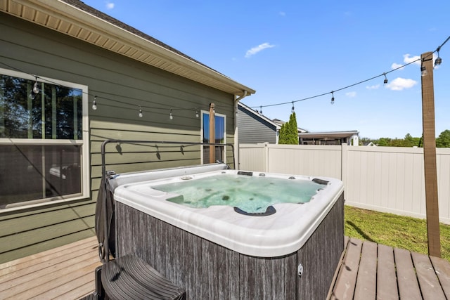 wooden terrace featuring a hot tub and fence