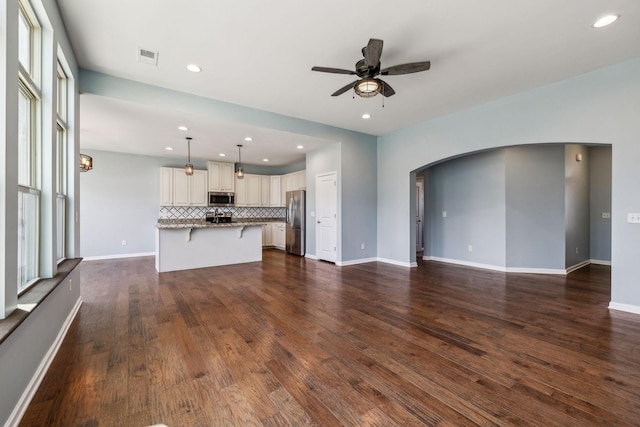 unfurnished living room with a ceiling fan, arched walkways, recessed lighting, and visible vents