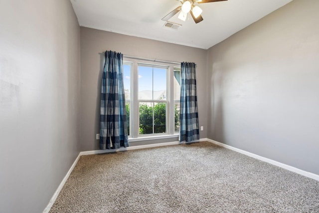 carpeted empty room with baseboards, a ceiling fan, and visible vents
