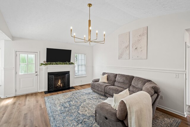 living area featuring a notable chandelier, a healthy amount of sunlight, lofted ceiling, and wood finished floors