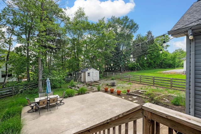 view of patio / terrace featuring an outdoor structure, a fenced backyard, a shed, and outdoor dining space