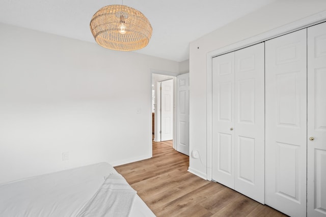 unfurnished bedroom featuring baseboards, a closet, and light wood-type flooring