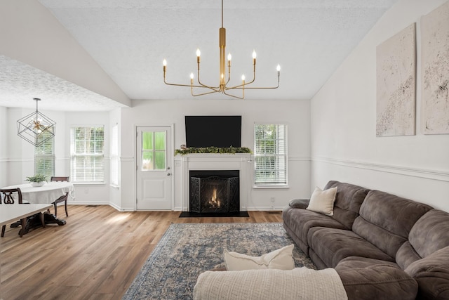 living area with a notable chandelier, wood finished floors, and lofted ceiling