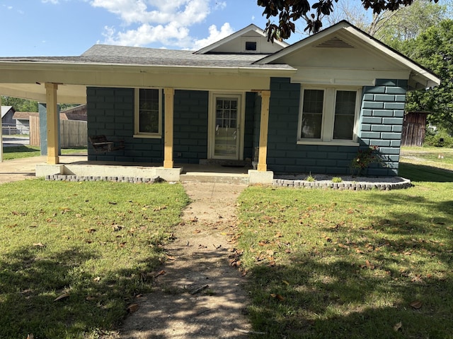 view of front of house with a front lawn, roof with shingles, and concrete block siding