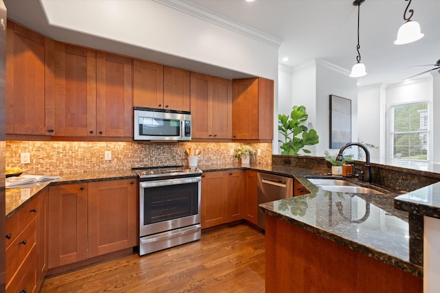 kitchen featuring brown cabinets, appliances with stainless steel finishes, ornamental molding, and a sink