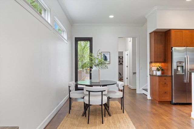 dining space featuring baseboards, ornamental molding, and light wood-style flooring