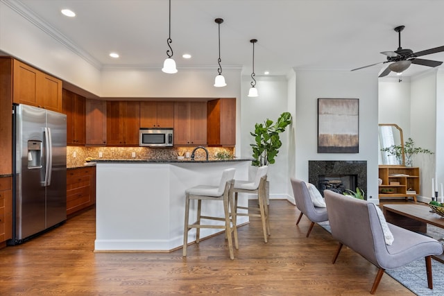kitchen featuring crown molding, appliances with stainless steel finishes, brown cabinets, and tasteful backsplash