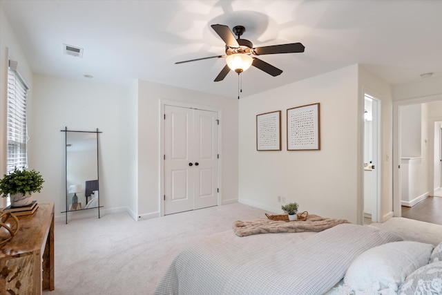 bedroom featuring light carpet, a ceiling fan, baseboards, visible vents, and a closet