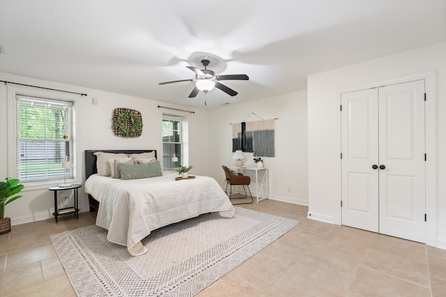 bedroom with a ceiling fan, baseboards, multiple windows, and light tile patterned floors