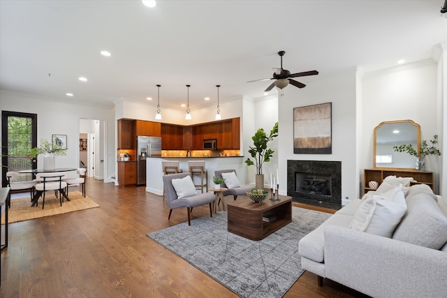 living area featuring a high end fireplace, ceiling fan, ornamental molding, and recessed lighting