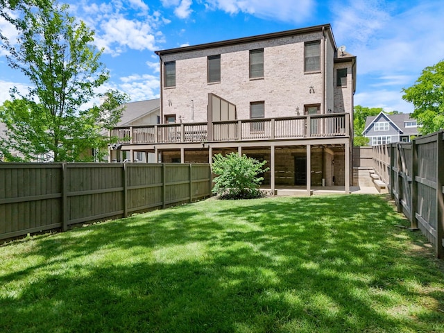 back of house featuring a lawn, brick siding, a wooden deck, and a fenced backyard