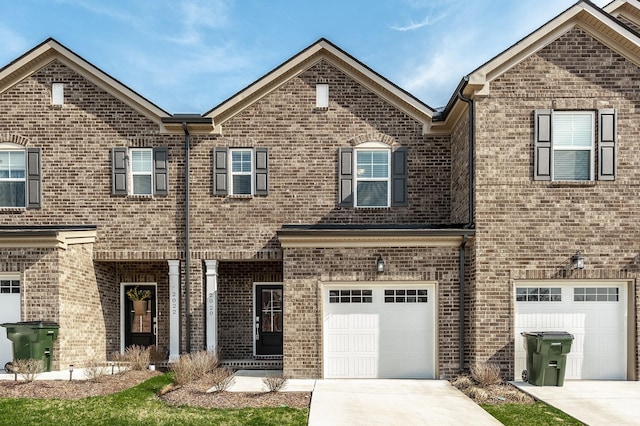 townhome / multi-family property featuring an attached garage, driveway, and brick siding
