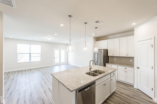 kitchen with appliances with stainless steel finishes, a sink, light wood-type flooring, backsplash, and visible vents