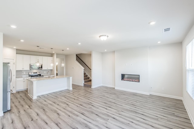 unfurnished living room with recessed lighting, visible vents, and light wood-type flooring
