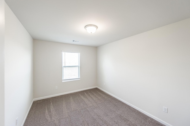 carpeted spare room featuring baseboards and visible vents