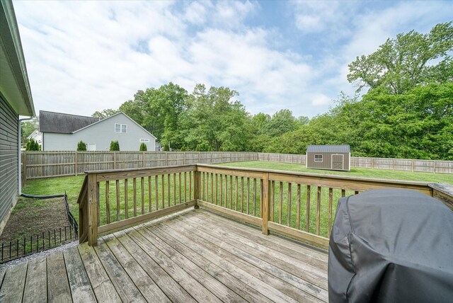wooden deck featuring an outdoor structure, a fenced backyard, a lawn, and a shed