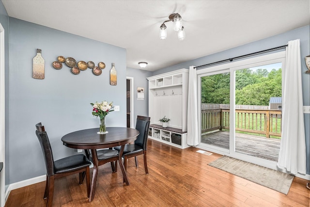 dining space with baseboards, visible vents, and wood finished floors