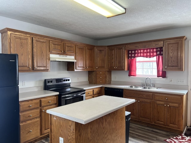 kitchen featuring a textured ceiling, under cabinet range hood, a sink, dark wood finished floors, and black appliances