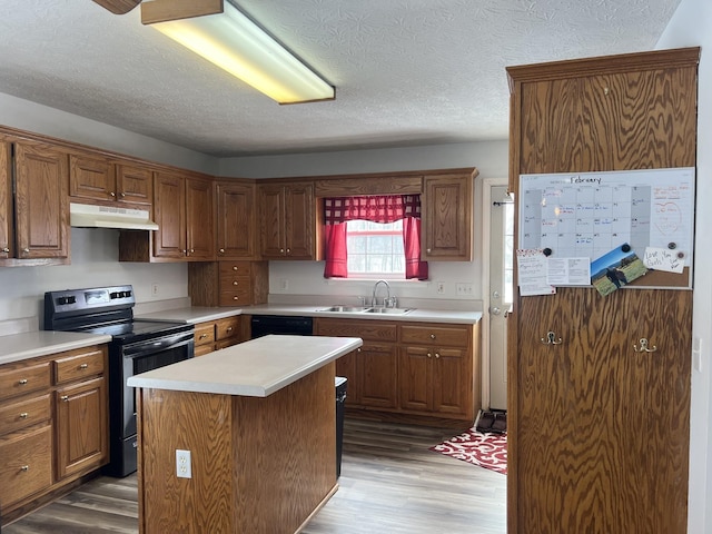 kitchen featuring stainless steel electric stove, under cabinet range hood, a sink, and wood finished floors