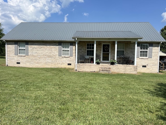 back of property featuring a lawn, metal roof, brick siding, and crawl space