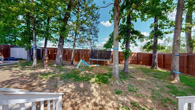 view of yard featuring a fenced backyard, a trampoline, and an outbuilding