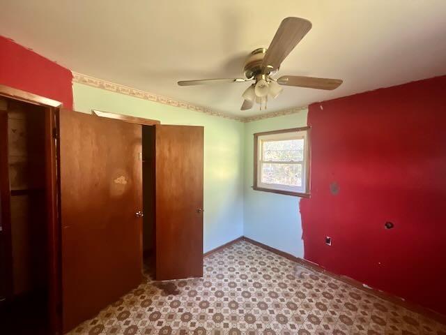unfurnished bedroom with tile patterned floors, ceiling fan, baseboards, and a closet