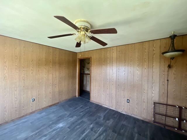 spare room featuring wooden walls, ceiling fan, and wood finished floors