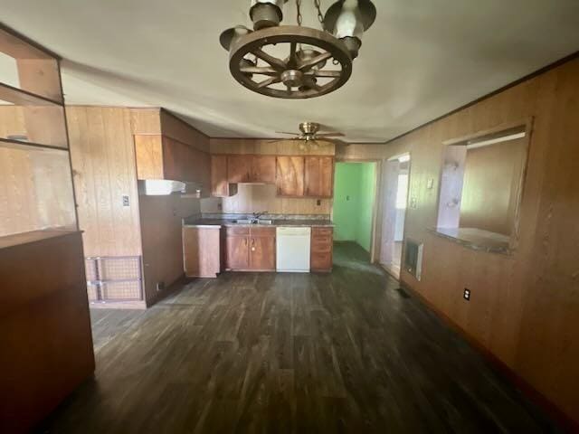 kitchen featuring dark wood-style flooring, white dishwasher, wood walls, brown cabinets, and ceiling fan with notable chandelier