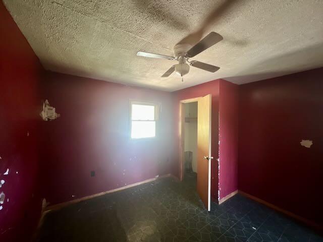 unfurnished bedroom featuring a ceiling fan, a textured ceiling, and baseboards