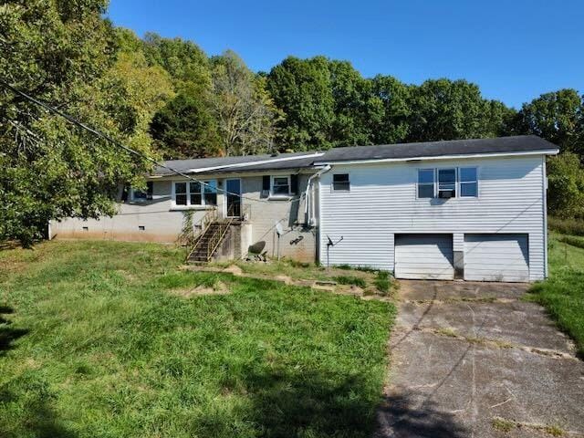 single story home featuring a view of trees, an attached garage, concrete driveway, and a front lawn