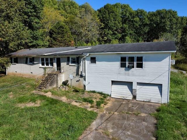ranch-style home with a view of trees, an attached garage, driveway, and a front yard