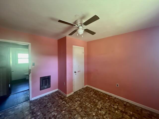 unfurnished room featuring baseboards, a ceiling fan, and a glass covered fireplace