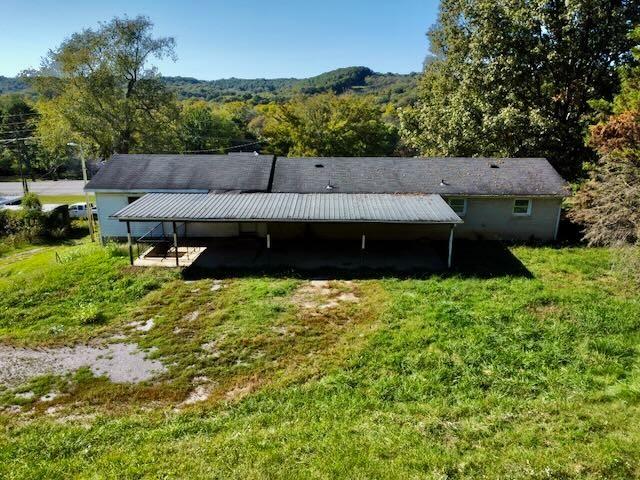back of property featuring a lawn and a wooded view