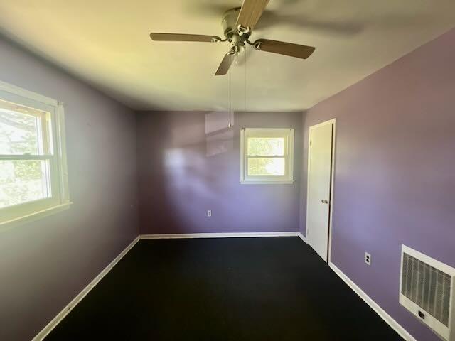 unfurnished room with baseboards, visible vents, and ceiling fan