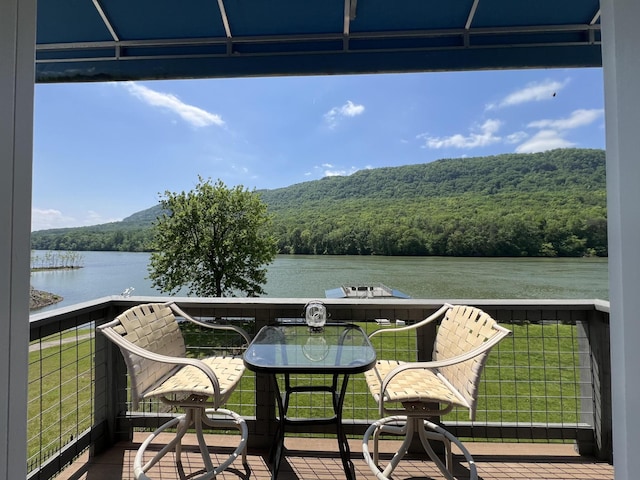 balcony featuring a forest view and a water view