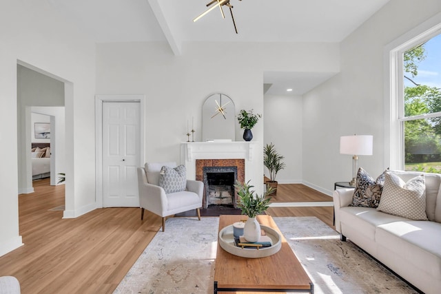 living area featuring baseboards, beamed ceiling, light wood finished floors, and a tile fireplace