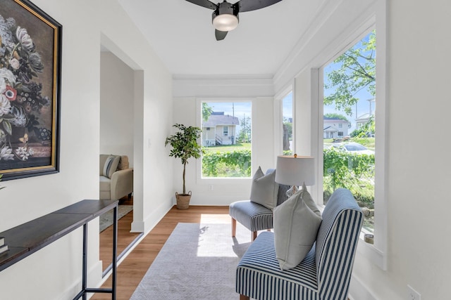 living area with baseboards, a ceiling fan, and wood finished floors