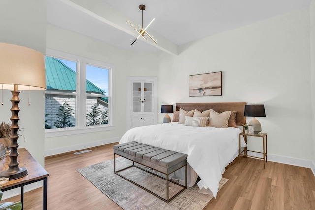bedroom with baseboards, wood finished floors, and an inviting chandelier