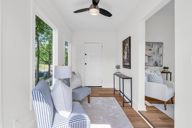 living area featuring baseboards, ceiling fan, and wood finished floors